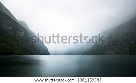 Paddeling with a kayak through the beautiful fjord landscape with high waterfalls to the famous Geiranger Fjord in Norway