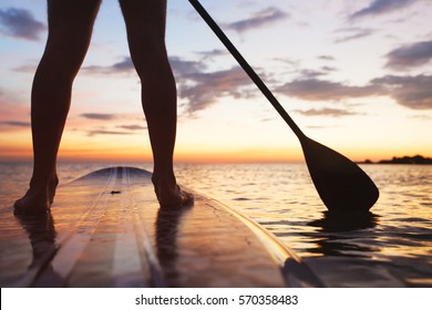 paddle board on the beach, close up of standing legs and paddle