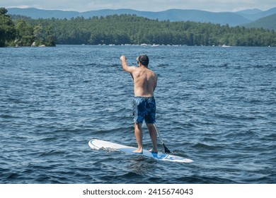 A paddle boarder enjoying a view of the White Mountains cruising on New Hampshire's Lake Winnipesaukee - Powered by Shutterstock