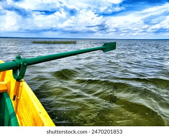The paddle of a boat and the water of a large lake in the background. Natural landscape, travel, recreation. boat paddle extends over a calm lake - Powered by Shutterstock
