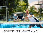 Paddle tennis player hitting the ball during mixed doubles match on outdoor court.