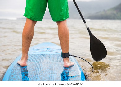 Paddleboard Man Paddling On SUP Stand Up Paddle Board On Lake. Closeup Of Feet And Legs.