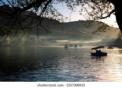 Paddleboats on the lake with haze in the forest at sunset. Leisure time activities concept photo. Selective focus.