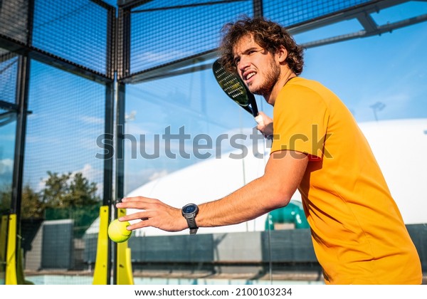 Padel or tennis player prepares to serve a tennis\
ball during a match - Trainer teaches boy how to play padel on\
outdoor tennis court
