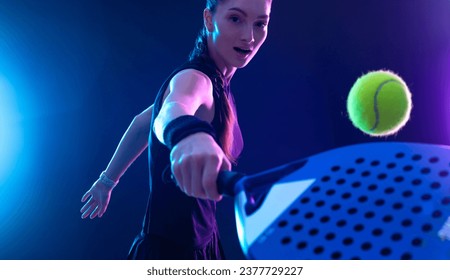 Padel tennis player with racket on tournament. Girl athlete with paddle racket on court with neon colors. Sport concept. Download a high quality photo for design of a sports app or tour events. - Powered by Shutterstock