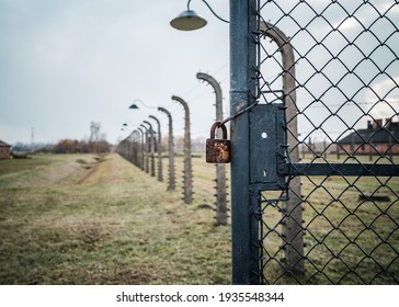 Padlock and chain on gate of world war 2 concentration prisoner of war camp locked with high voltage electric barb wire fence and old retro guard spot lights