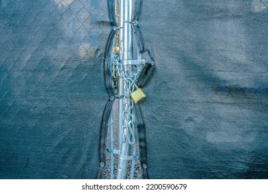 Padlock With Chainlink On A Mesh Gate Fence With Cover At Downtown Tucson, Arizona. Gate With Black Cover And Padlock With Chainlink In The Middle.