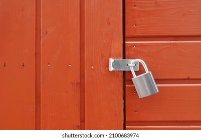 padlock on locked door of red wood cabin or wooden shed