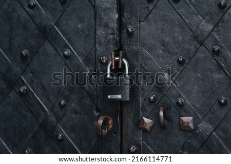 Padlock on an old forged black metal door with stripes and rivets. Fragment of the Boim Chapel in Lviv, Ukraine. Vintage background closeup. Closed passage and protection concept.