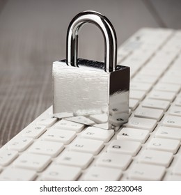 padlock and white computer keyboard on the wooden office table. privacy protection, encrypted connection concept