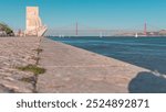 Padrao dos Descobrimentos (Monument to the Discoveries) celebrates the Portuguese who took part in the Age of Discovery timelapse, Lisbon, Portugal. Waterfront with river and bridge on a background