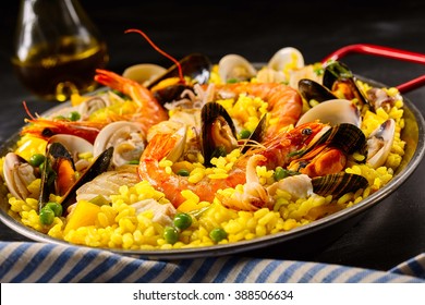 Paella a la margarita with shellfish including pink prawns, clams and mussels on saffron rice with peas for a delicious seafood meal, close up view