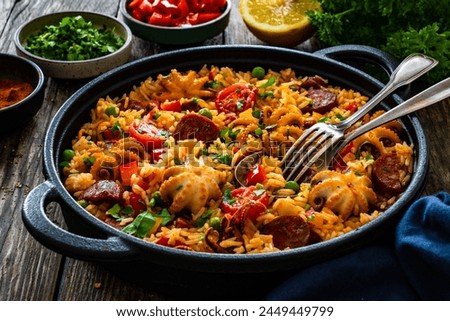 Paella seafood and chorizo in cooking pan on wooden table 