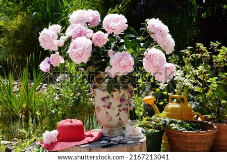 Paeonia Lactiflora, Beautiful Large Bouquet Of Peony Flowers And Paper Hat On The Wood Table In The Green Summer Garden.