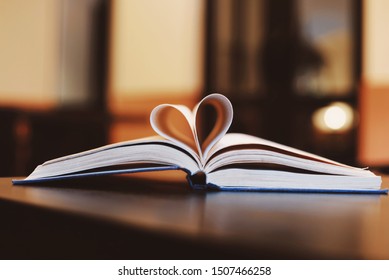 A Page Of Book Paper Making Heart Shape On Table.