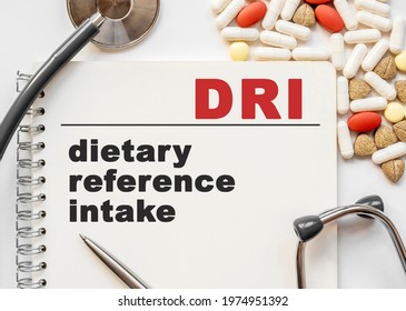 Page in notebook with DRI on white background with stethoscope and group of pill. Medical concept. Term and abbreviation. dietary reference intake