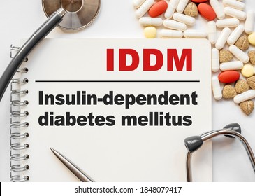 Page in notebook with IDDM Insulin-dependent diabetes mellitus on white background with stethoscope and group of pill. Medical concept. Term and abbreviation