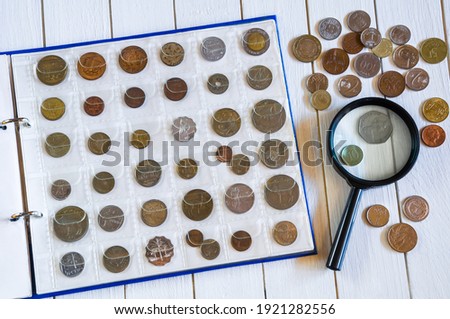 Page of numismatics album with different coins on a white wooden table
