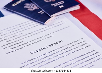 Page of paper with words Customs Clearance next to American passports on American flag background - Powered by Shutterstock