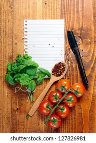 Page Of White Blank Lined Paper Torn From A Ringbound Notebook On A Wooden Table With Fresh Herbs, Tomatoes And Peppercorns In A Wooden Spoon With A Pen To Write Your Recipe, Menu Or Grocery List