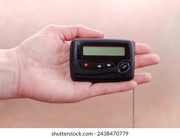 pager in close-up, an old retro communication device, in a female hand on a beige background