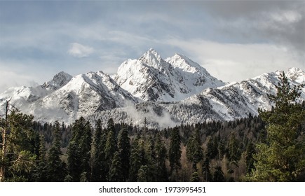 Pagorama of the snow-capped mountains of arkhyz at sunset. The sun's rays showed the texture of the mountains. In them, most of the photo shows a forest, part of which is covered with snow. - Powered by Shutterstock