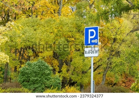 Paid parking road sign indicating the time against the backdrop of colorful trees in an autumn park
