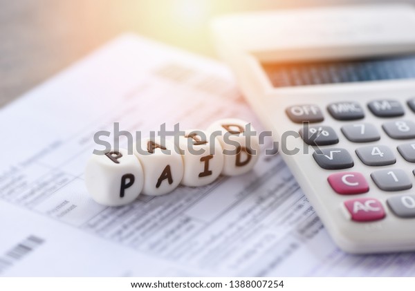 Paid words and calculator on\
invoice bill paper for time paid payment at office business\
finances