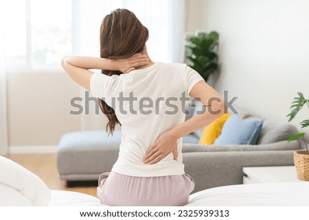 Pain body muscles stiff problem, asian young woman painful back, neck ache from work hand holding massaging rubbing shoulder hurt, sore sitting on bed while wake up at home. Health care and medicine.