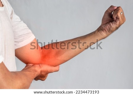 Pain in the elbow joint of Southeast Asian young man. Concept of elbow pain, injury, rheumatism or osteoarthritis.