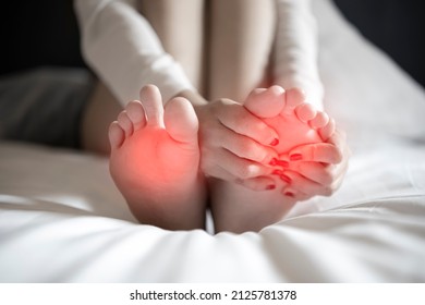 Pain In The Foot, Girl Holds Her Hands To Her Feet, Foot Massage, Cramp, Muscular Spasm, Red Accent On Foot, Black And White Photo, Close-up