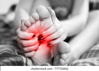 Pain In The Foot, Girl Holds Her Hands To Her Feet, Foot Massage, Cramp, Muscular Spasm, Red Accent On Foot, Black And White Photo, Close-up