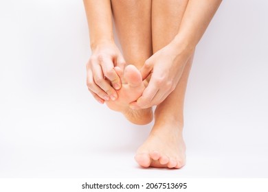 Pain in the foot and toes from uncomfortable shoes. A woman holds a sore foot with her hands on a white background. Pathology of bone structures, flat feet. Cramp, convulsion, spasm. Orthodontics - Shutterstock ID 2067513695
