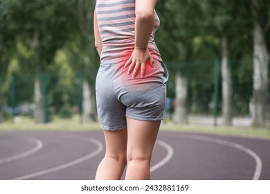 Pain in the hip during training, muscles cramped, massage on a sports ground after workout, health problems concept