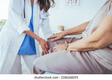 Pain in the knee. Good looking nice aged woman holding her knee and looking at her doctor while explaining where she feels pain. Support for strained muscles. Doctor fixing womans knee with hands - Powered by Shutterstock