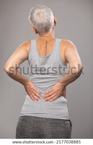 Pain in lower back, backache, sciatica, senior old woman with short gray hair and body and spinal muscle problems