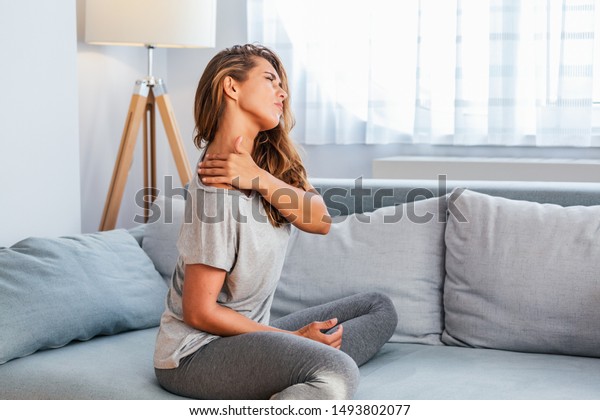 Pain\
in the shoulder. Upper arm pain, People with body-muscles problem,\
Healthcare And Medicine concept. Attractive woman sitting on the\
bed and holding painful shoulder with another\
hand.