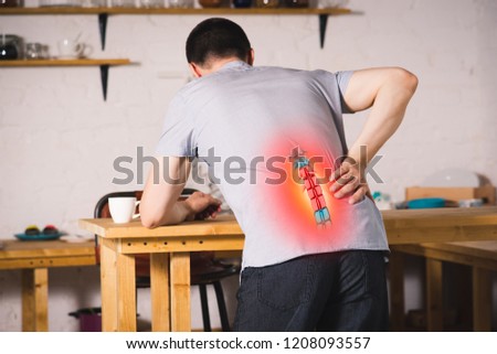 Pain in the spine, a man with backache at home, injury in the lower back, photo with highlighted skeleton