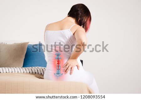Pain in the spine, woman with backache at home, injury in the lower back, photo with highlighted skeleton