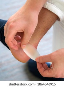 Painful Heel Wound On Mans Feet Caused By New Shoes. Mans Hands Applying Plaster On Terrible Blister On Human Heel. Wet Bloody Painful Skin On Man Foot With Medical Plaster