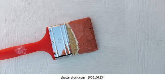 Paint Brush In Brown Paint On The Background Of A White Painted Wall.Space For The Text.