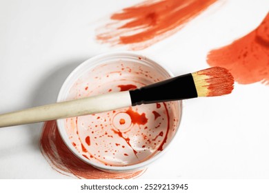 Paint brush on top of paint can with red paint on white background. - Powered by Shutterstock