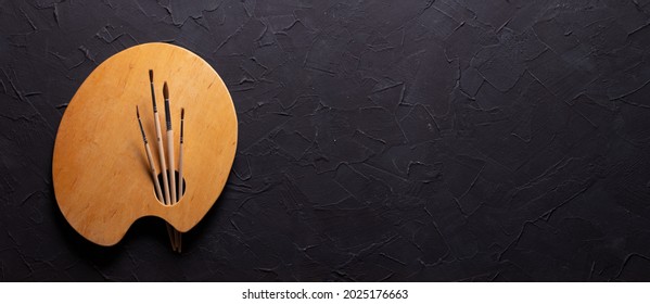 Paint brush and palette at black abstract background texture. Paintbrush for oil painting still life. Art concept - Powered by Shutterstock