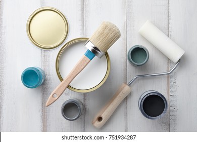 Paint brush, sponge roller, paints, waxes and other painting or decorating supplies on white wooden planks, top view - Powered by Shutterstock