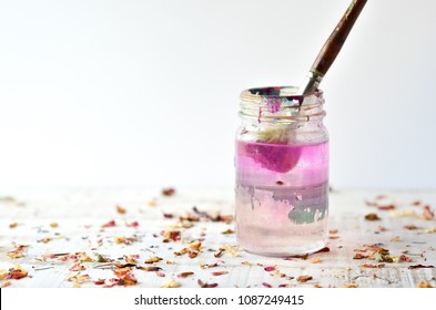 Paint Brush in water jar with dried flowers on white background - Powered by Shutterstock