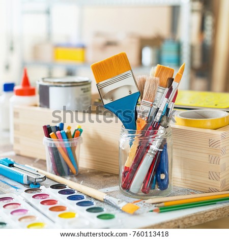 Paint brushes and crafting supplies on the table in a workshop.