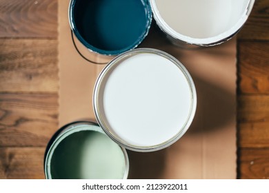 Paint Cans During House Renovation, Process Of Choosing Paint For The Walls, Different Colors Of White, Green And Blue On Wooden Floor