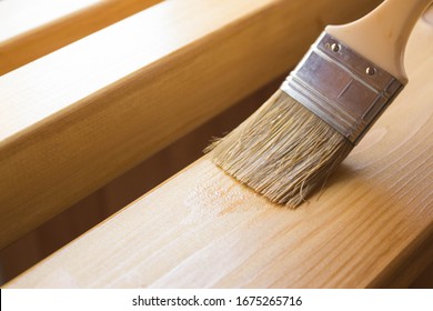 Paint coating and protection of wooden surfaces.Brush that covers wooden planks and beams with varnish for interior work in the color of oak.