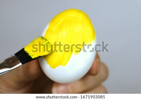 Paint the eggs with yellow paint. Preparing for Easter. Selective focus. Close-up