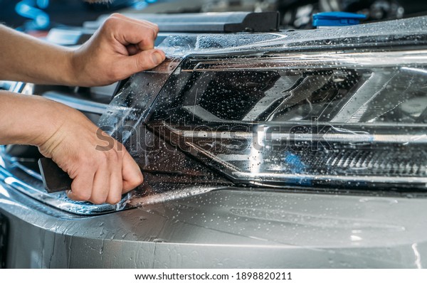 Paint\
Protection Film for cars or anti-gravel protection coating wrapping\
on headlight of new vehicle. Car detailing\
concept